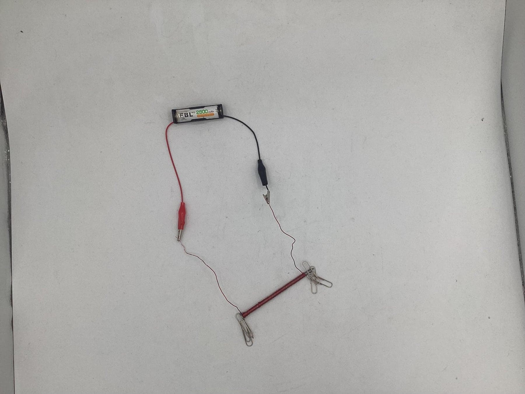 A nail wrapped in wire connected to a battery pack as an electromagnet.