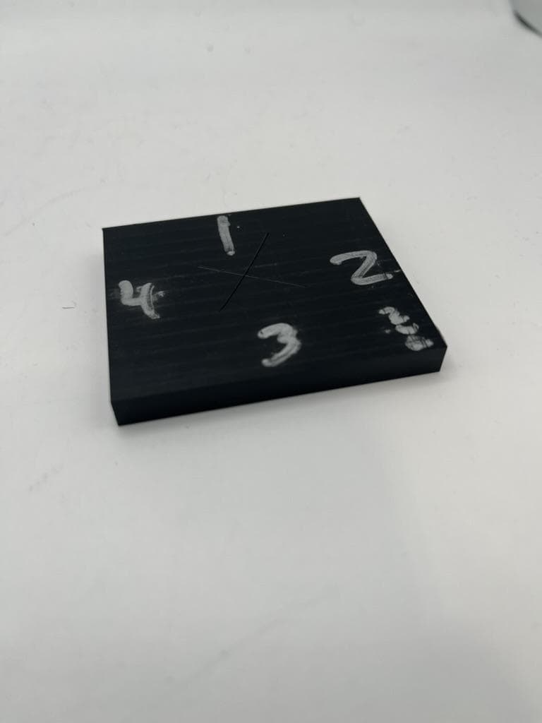 Machined black plate with its edges hand-numbered for orientation.