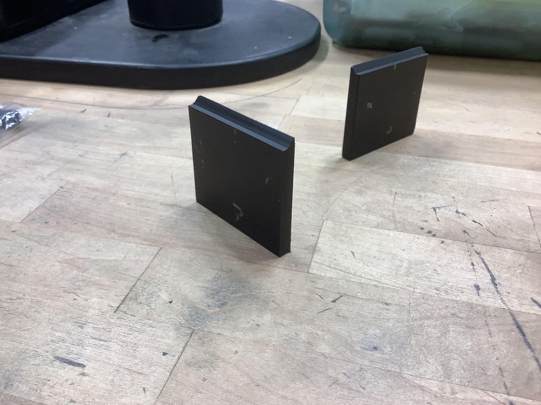 Two finished black base plates standing on a shop floor.