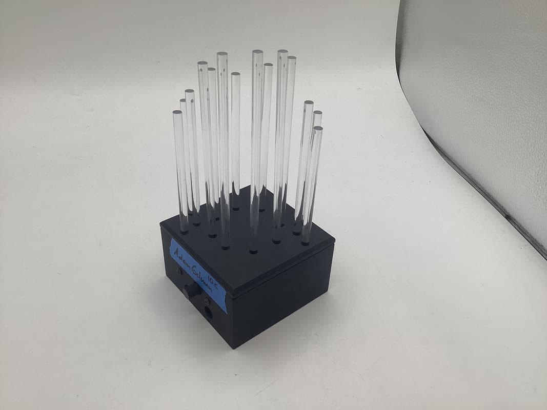 The finished light sculpture with LEDs off: clear acrylic rods of different heights in a black square base.