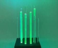 Acrylic rods of varied heights, four glowing green, standing in a black base against a green-lit background.