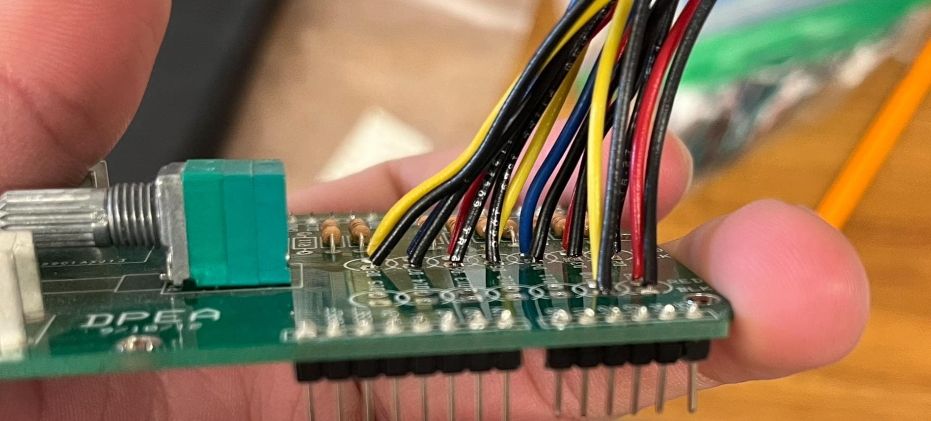 Close view of the controller board: a green PCB with a potentiometer, resistors, pin headers and a dense bundle of colored wires soldered to it.