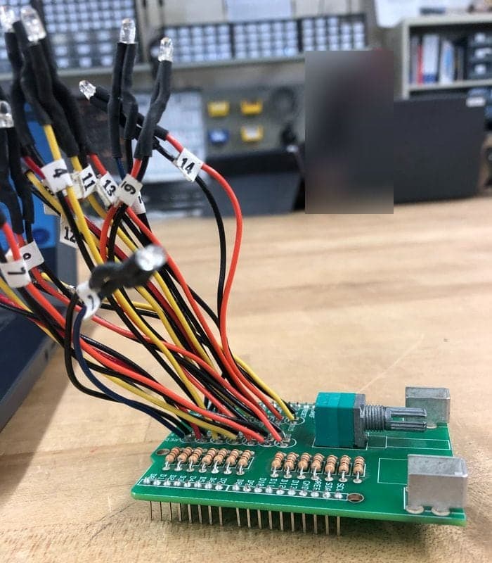Green circuit board seen edge-on with a bundle of red, yellow and black wires rising to small clear LEDs in black heat-shrink, with numbered wire tags.