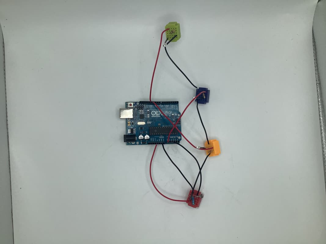 Overhead view of an Arduino Uno wired to four small LED breadboards and a light sensor.